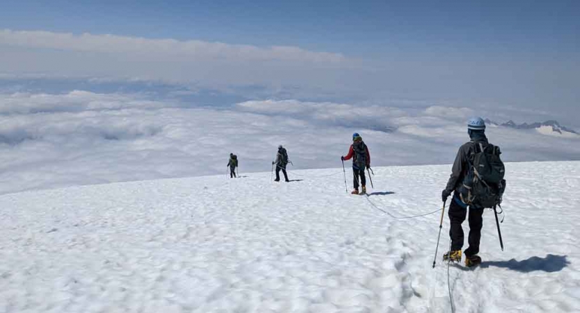 a group of students on a mountaineering course traverse a snowy mountainous landscape
